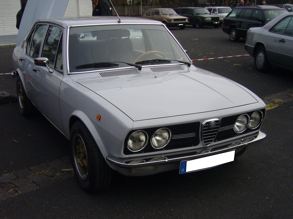 Alfa Romeo Alfetta Limousine, gebaut in den Jahren von 1972 bis 1984. Alfetta = Kleiner Alfa, so hießen schon in den 1950er Jahren die Rennwagen von Alfa Romeo. Auch diese viertürige Alfa Romeo Limousine hatte sportliches Temperament. Hier wurde ein Modell bis Baujahr 1977 abgelichtet. Dieses ist an den runden Frontscheinwerfern zu erkennen. Die Alfetta war in etlichen Motorisierungen als Benziner oder Dieselfahrzeug lieferbar. Der hier gezeigte Wagen ist eine Alfetta 1.6. Der Vierzylinderreihenmotor hat einen Hubraum von 1570 cm³ und leistet 108 PS. Oldtimertreffen an Mo´s Bikertreff in Krefeld am 10.11.2024.