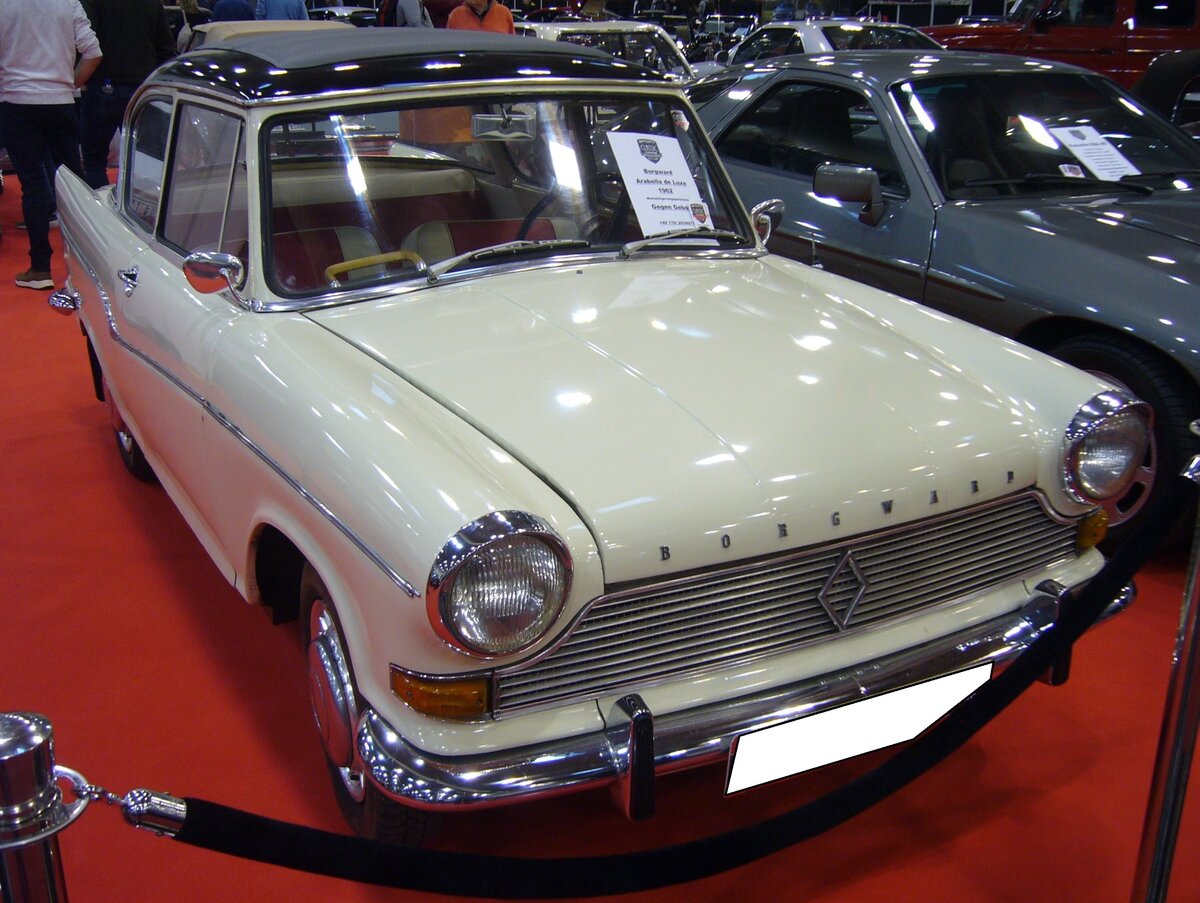 Borgward Arabella de Luxe in der Farbkombination arkonaweiß/diamantschwarz, gebaut in den Jahren von 1959 bis 1963. Die  Arabella  kam als Lloyd LP 900 auf den Markt und war optisch und technisch gut gelungen. Aber, wie so oft im Borgward Konzern, zu überstürzt und daher nicht besonders ausgereift auf den Markt gekommen. Das war dem Ruf des Modells nicht besonders zuträglich. Es gab die Modelle Arabella und ab 1960 zusätzlich die Arabella de Luxe. Im November 1960 schlug eine Arabella mit ein Kaufpreis von DM 5230,00 zu Buche und das de Luxe Modell mit DM 5730,00. Der Vierzylinderboxermotor aus Leichtmetall hat einen Hubraum von 897 cm³. Während er in der Arabella 38 PS leistet, kommt die Arabella de Luxe durch eine andere Vergaserbestückung auf eine Leistung von 45 PS. Die Limousine wurde kurz vor dem wirtschaftlichen Zusammenbruch des Unternehmens in Borgward Arabella umgetauft. Die gezeigte Arabella de Luxe wurde 1962 erstmalig zugelassen. Essen Motor Show am 04.12.2024.