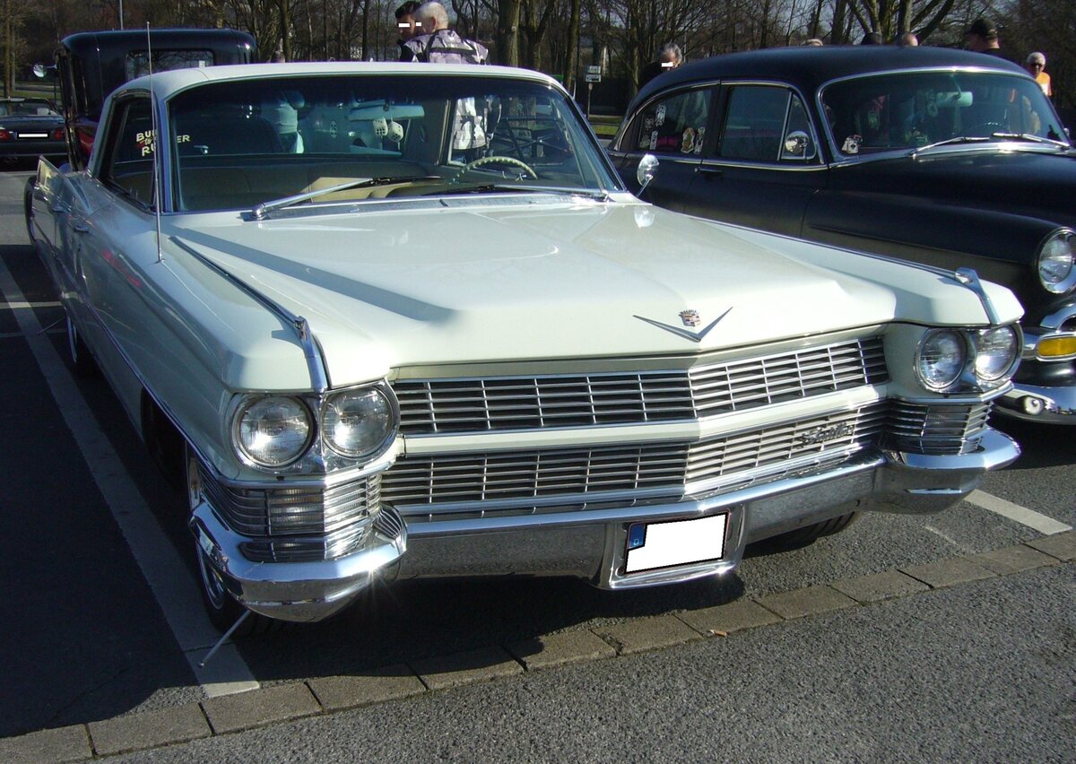 Cadillac Series 62 Hardtop Coupe aus dem Modelljahr 1964. Von diesem Coupe-Modell verkaufte die GM-Luxus-Division Cadillac in diesem Modelljahr die Coupe´s ab einem Kaufpreis von US$ 5048,00. Das gezeigte Coupe ist im damals sehr beliebten Farbton aspen white lackiert. In diesem Modelljahr waren alle Cadillac-Fahrzeuge mit dem neuen V8-Motor mit einem Hubraum von 429 cui (7030 cm³) und einer Leistung von 340 PS ausgerüstet. Oldtimerbrunch am Cafe del sol in Gelsenkirchen am 09.03.2025.