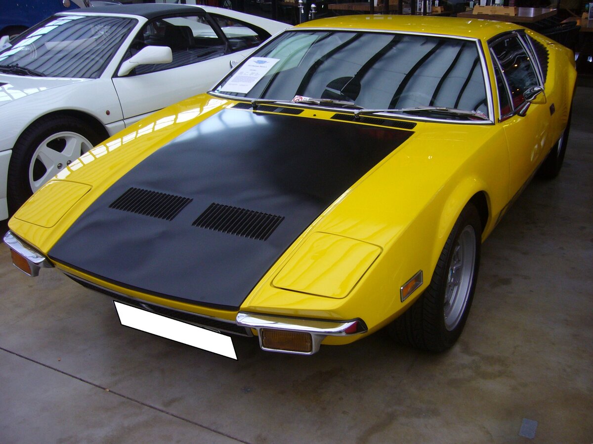 De Tomaso Pantera L aus dem Jahr 1972. Das L in der Typenbezeichnung stand für Lusso, also Luxus. Der Argentinier Alejandro De Tomaso gründete 1959 in der Nähe von Modena die De Tomaso Automobili SpA. Im Jahr 1971 wurde der Pantera als Nachfolger des legendären  Mangusta  vorgestellt. Die Karosserie wurde vom berühmten US-amerikanischen Autodesigner Tom Tjaarda (*1934 +2017) gezeichnet. Der Motor war als Mittelmotor verbaut und stammte aus dem Regal von Ford/USA. Dieser V8´er hat einen Hubraum von 5763 cm³ und leistet, je nach Vergaserbestückung, zwischen 280 PS und 400 PS. Die Höchstgeschwindigkeit wurde damals mit 257 km/h angegeben. Classic Remise Düsseldorf am 01.11.2024.