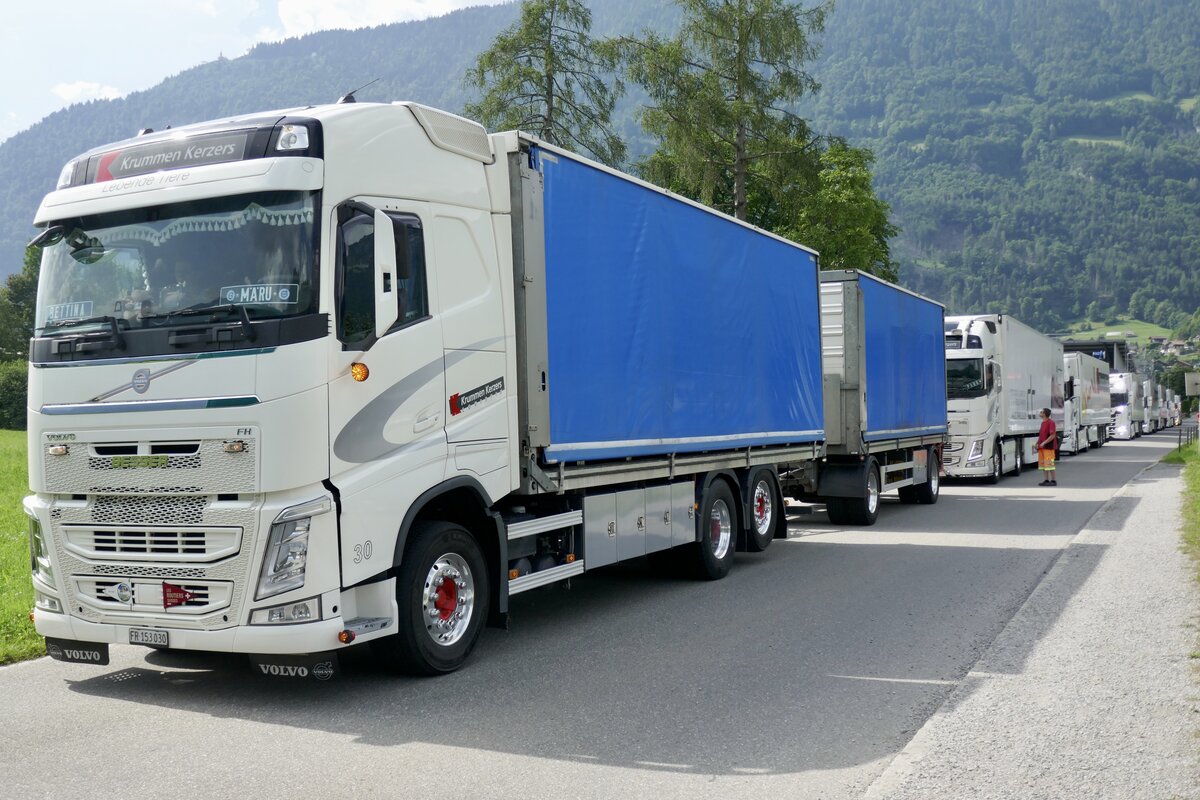 Ein Volvo FH Hängerzug und weitere LKW von Krummen Kerzers die am 28.6.24 auf Einlass aufs Trucker Festival Gelände warten in Bönigen.