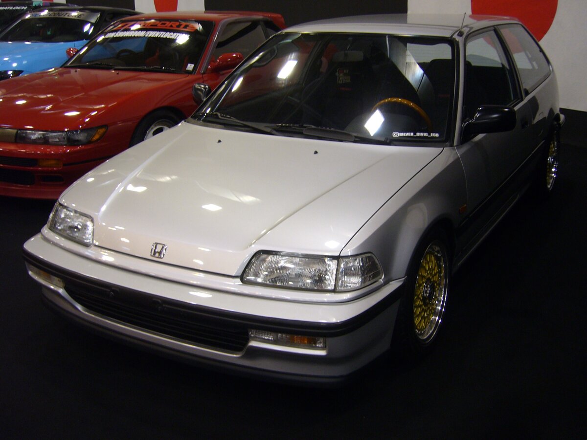 Honda Civic MK4 Steilhecklimousine. Die seit 1972 produzierte Baureihe  Civic  ist das Volumenmodell der japanischen Marke. Seit dem Jahr 1987 wurde, die hier gezeigte, vierte Serie, in etlichen Karosserieversionen produziert. Für den europäischen Markt erfolgte die Produktion im englischen Swindon. Ursprünglich handelte es sich bei diesem Auto um das Basismodell EC8. Es war das am schwächsten motorisierte Modell dieser Baureihe. Der Vierzylinderreihenmotor hat serienmäßig einen Hubraum von 1343 cm³ und leistet 75 PS. Als Spitzengeschwindigkeit gab das Werk 168 km/h an. Essen Motor Show am 04.12.2024.