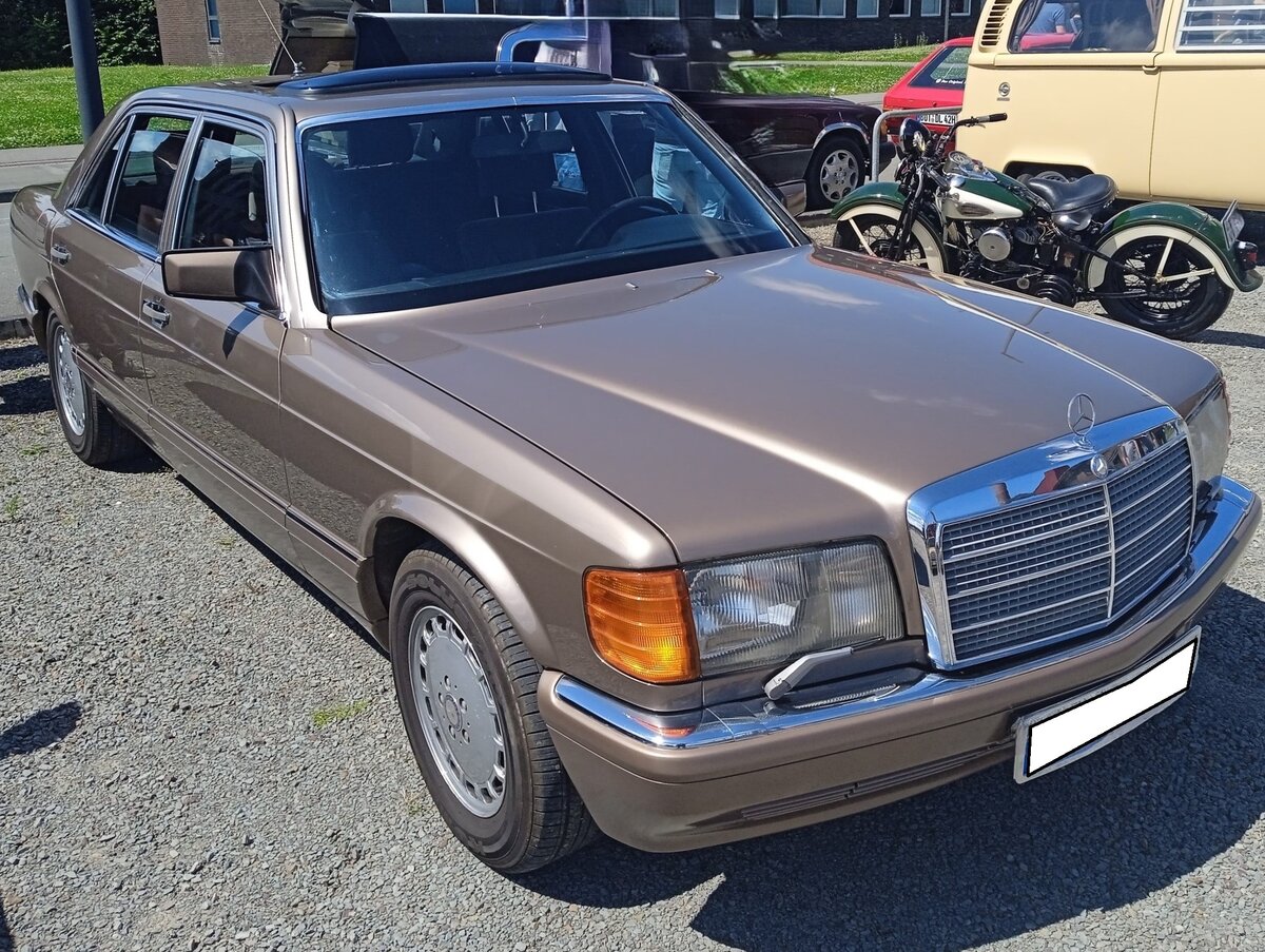 Mercedes Benz W126 560SEL. Die Baureihe W126, die so genannte S-Klasse wurde auf der IAA des Jahres 1979 vorgestellt. Vorrangiges Konstruktionsziel für diese Typenfamilie war die Verringerung des Gewichts und des Luftwiderstandes zur Verbrauchsreduzierung. Die Modellreihe war mit zwei verschiedenen Radständen lieferbar: Die SE-Modelle mit 2930 mm und die SEL-Modelle 3070 mm. Es wurden Der Kunde konnte zwischen etlichen Sechszylinderreihen- und V8-Motoren wählen. Der gezeigte 560 SEL war das absolute Spitzenmodell dieser Baureihe und verkaufte sich ab seiner Markteinführung 1985 genau 71.700 mal. Bei seiner Markteinführung musste man für den Erwerb eines solchen Autos mindestens DM 121.400,00 anlegen. Zum Ende der Bauzeit waren es schon DM 141.600,00. Bei einem Hubraum von 4973 cm³ leistet der Motor je nach Baujahr und Auslieferungsland zwischen 223 PS und 265 PS. Oldtimer-Revival auf dem Gelände der Kokerei Zollverein in Essen am 28.07.2024.