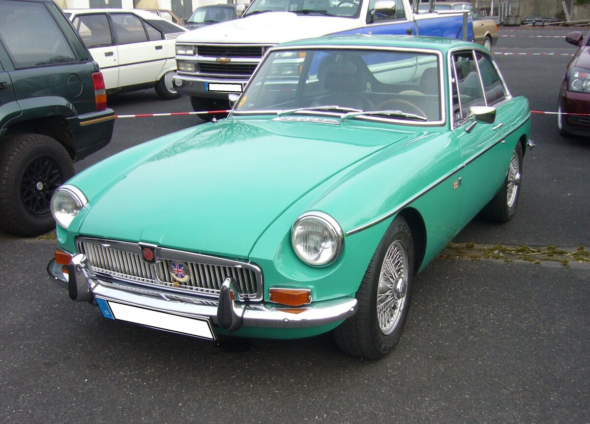 MG B GT 1800. Während der MG B Roadster bereits 1962 eingeführt wurde, kam der als 2+2 Sitzer ausgelegte MG B GT, erst im Oktober 1965 auf den Markt. Er war, genau wie der Roadster, bis 1980 im Verkaufsprogramm der Marke aus Coventry. Während sich das Roadster Modell während der gesamten Produktionszeit fast 400.000 mal verkaufte, wurde vom GT Modell genau 125.282 Einheiten abgesetzt. Der Vierzylinderreihenmotor hat einen Hubraum von 1798 und leistet 92 PS. Die Höchstgeschwindigkeit lag bei 168 km/h. Der gezeigte Wagen wurde im Jahr 1966 produziert und dürfte im Farbton balboa light aqua lackiert sein. Oldtimertreffen an Mo´s Bikertreff in Krefeld am 10.11.2024.