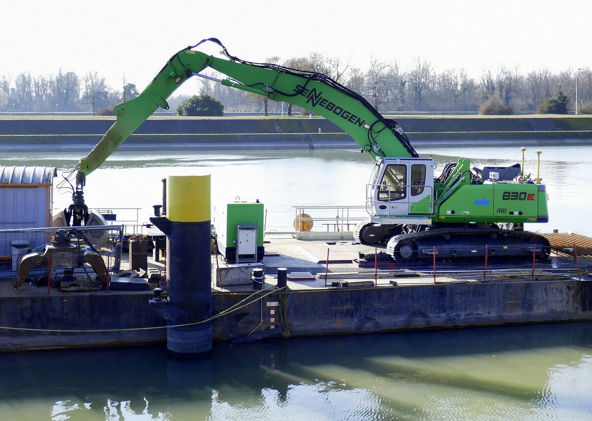 Sennebogen 830E, Abbruchbagger, auf einem Arbeitsschiff nahe der Rheinstaustufe Vogelgrün/Elsaß, Feb.2025