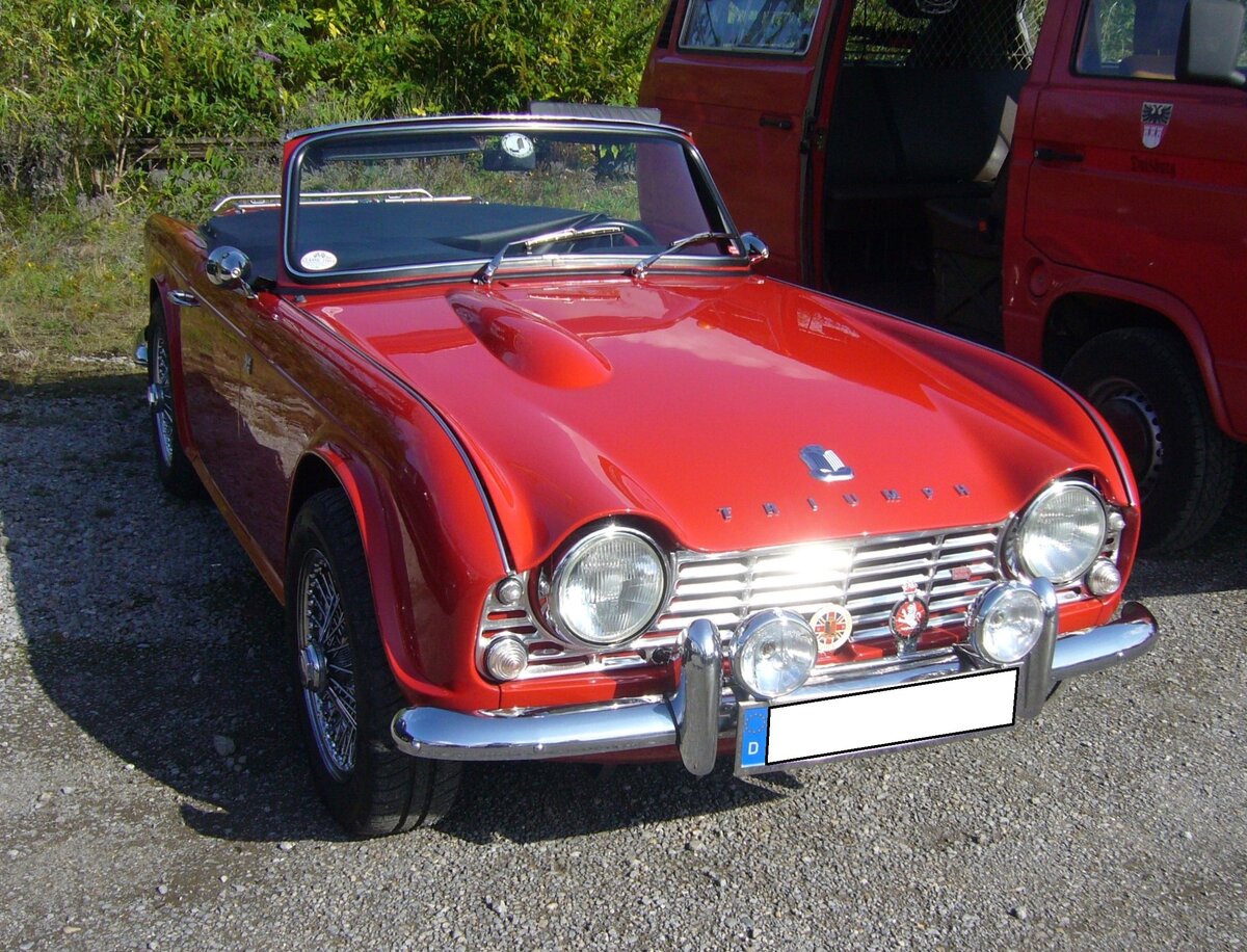 Triumph TR4 aus dem Jahr 1962 im Farbton signal red. Verglichen mit seinem legendären Vorgänger TR3, bot der von Giovanni Michelotti gezeichnete TR4, wesentlich mehr Komfort. Obwohl der TR4 über versenkbare Seitenscheiben, ein wesentlich besseres Verdeck und über einen Kofferraum verfügte, verlor er nichts von seinen sportlichen Qualitäten. Mit dem völlig neuen Vierzylinderreihenmotor mit einem Hubraum von 2138 cm³ und einer Leistung von 105 PS erreichte das Modell ein Leistungsniveau das sich ohne weiteres mit den Konkurrenten in dieser Kategorie messen konnte. Die Höchstgeschwindigkeit wurde mit 175 km/h angegeben. Der relativ günstige Preis sorgte von 1962 bis 1965 für ein Produktionsvolumen von rund 40.000 Fahrzeugen. 10. Oldtimertreffen des AMC Duisburg am 25.08.2024 am LaPaDu Duisburg.