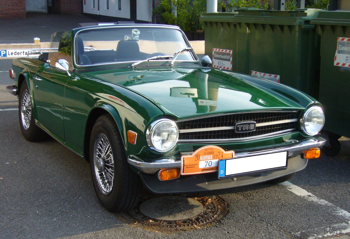 Triumph TR6 im Farbton emerald green, produziert in den Jahren von 1970 bis 1976. Im Jahr 1970 erschien der letzte Abkömmling der klassischen Triumph TR-Baureihe in Form des TR6. Die Karosserie hatte der legendäre Italiener Giovanni Michelotti (*1921 +1980) gezeichnet. Der Sechszylinderreihenmotor des TR6 stammt vom Triumph 2000 und wurde auf 2498 cm³ Hubraum aufgebohrt. Dieser Motor leistet 150 PS und beschleunigt den TR6 auf eine Höchstgeschwindigkeit von 190 km/h. Aufgrund der seitlichen Begrenzungsleuchten, gehe ich davon aus, dass es sich bei diesem Auto aus dem letzten Modelljahr um einen USA-Reimport handelt. 11. Saarner Oldtimer Cup am 01.09.2024 in Mülheim an der Ruhr-Saarn.