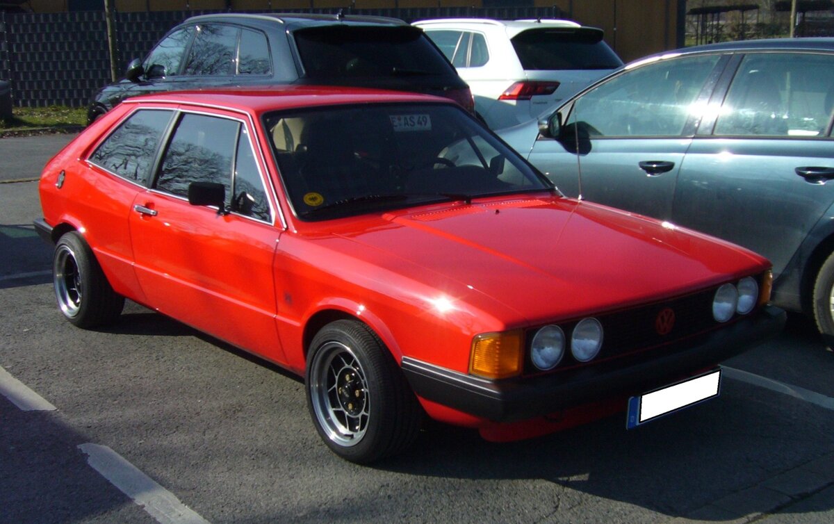 VW Scirocco der ersten Serie, wie er von 1974 bis 1980 bei Karmann montiert wurde. Der abgelichtete Scirocco hat die recht  sportliche  GT-Ausstattung und wurde 1978 gebaut. Dieses ist an den Stoßstangen und den herum gezogenen, vorderen, Blinkern erkennbar. Ein solcher, ibizaroter, Scirocco stand mit einem Kaufpreis von DM 15.520,00 in den Preislisten der VW-Händler. Der quer eingebaute Vierzylinderreihenmotor hat einen Hubraum von 1588 cm³ und leistet 85 PS. Die Höchstgeschwindigkeit gab Volkswagen mit 172 km/h an. Oldtimerbrunch am Cafe del sol in Gelsenkirchen am 09.03.2025.