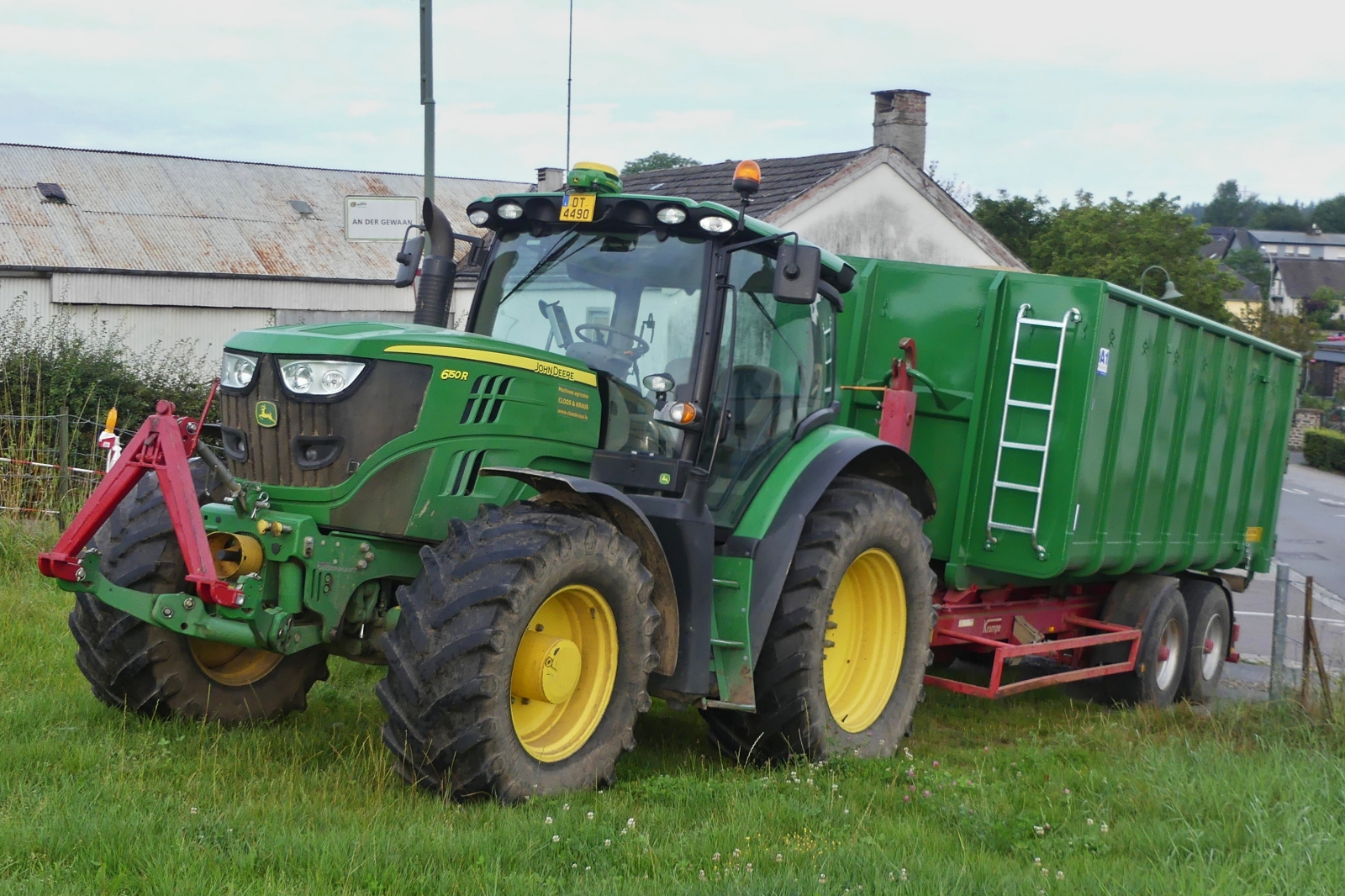 John Deere 6150R, mit Doppelachsigem Absetzkipper, steht in der Einfahrt einer Weide. 08.2024