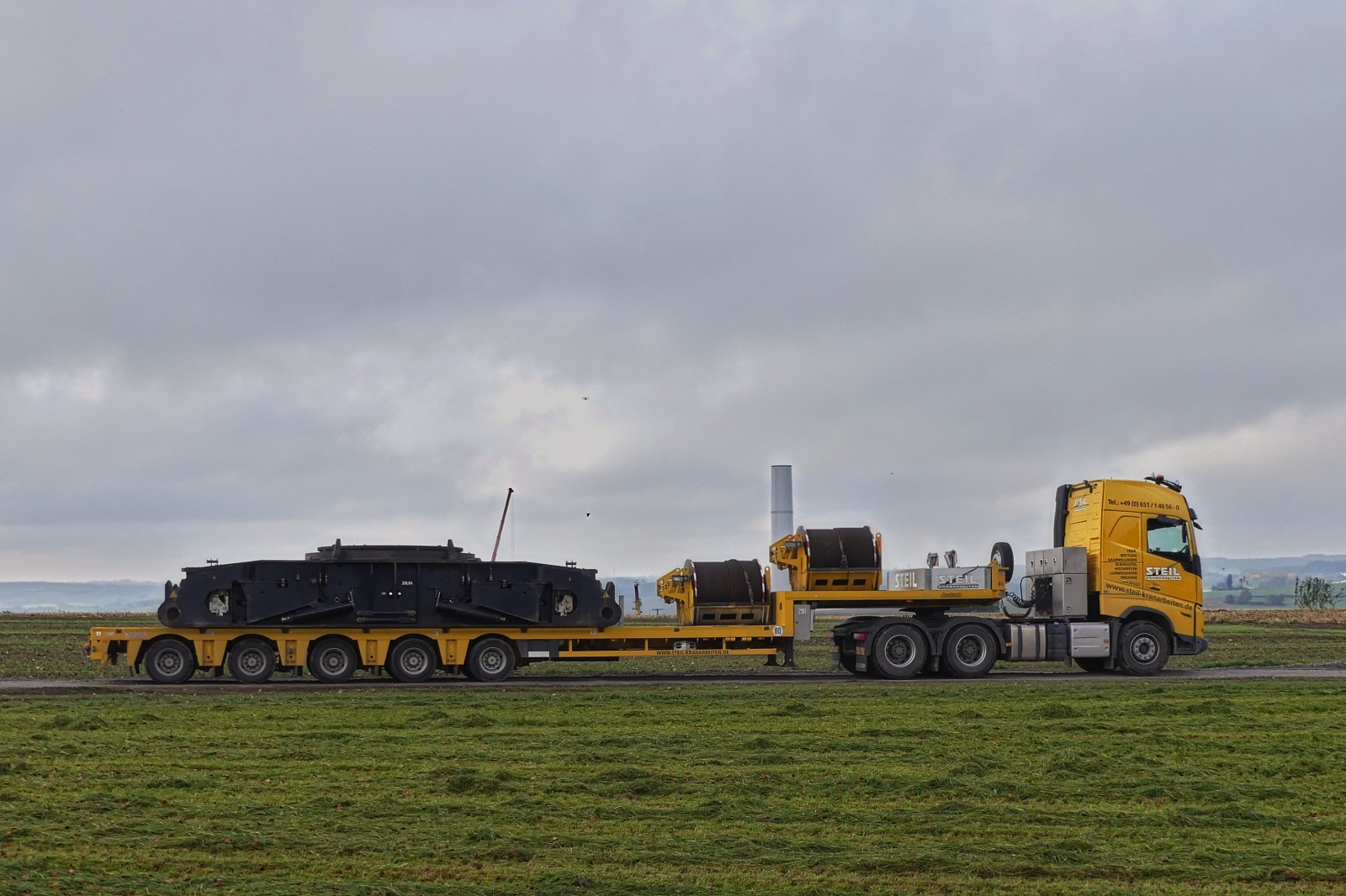 MB Schwerlastsattelzug, von Steil Kranarbeiten, mit Teilen von einem Demag CC 3800-1 Raupenkran, steht auf der Zufahrt zu einer Windkraftanlagen Baustelle. Wenn man sowas im Vorbeifahren von der Strae aus sieht muss man doch Anhalten oder. 25.10.2024