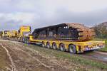 Der ganze Schwerlastauflieger ist belegt von einem Raupenantrieb des Demag Schwerlast Kranes.