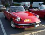 Alfa Romeo Spider 2.0 im Farbton rosso alfa aus dem Jahr 1987. Gereift und erwachsen bestritt der Spider sein zweites Lebensjahrzehnt. Optisch gab es nun deutliche Veränderungen. Kunststoffstoßfänger mit einem integrierten Grill vorne, ein unübersehbarer Kunststoffheckspoiler und einen  modernisierter  Innenraum sollten das  Aerodinamica  getaufte Auto aktuell erscheinen lassen. Spötter nannten es allerdings lieblos  Gummilippe . Die Baureihe war von 1986 bis 1989 im Verkaufsprogramm von Alfa Romeo. Der Vierzylinderreihenmotor hat einen Hubraum von 1962 cm³ und leistet 125 PS, bzw. 115 PS wenn ein Katalysator verbaut war. 11. Saarner Oldtimer Cup am 01.09.2024 in Mülheim an der Ruhr-Saarn.