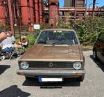 Frontansicht eines VW Golf 1 MK2 aus dem Jahr 1981. Der im Farbton sandmetallic lackierte Golf, ist unrestauriert und wurde erstmals im Oktober 1981 zugelassen. Der Vierzylinderreihenmotor hat einen Hubraum von 1457 cm³ und leistet 70 PS. Um die angegebenen Höchstgeschwindigkeit von 158 km/h zu erreichen, muss das Gehör des Fahrers allerdings sehr leidensfähig sein, da dieser Golf nur mit einem Vierganggetriebe ausgestattet ist. Somit ist die Geräuschkulisse im Innenraum dann enorm. Oldtimer-Revival auf dem Gelände der Kokerei Zollverein in Essen am 28.07.2024.