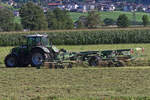 Fendt 724 Vario mit einem Heuwender, beim Schwaden von trockenem Heu im Zillertal, aufgenommen aus einem Zug.