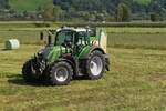 Fendt 720 Vario mit einer Rundballenpresse, bei der Heuernte im Zillertal, aufgenommen aus einem Zug. 08.2024