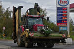 McCormick Traktor mit 3 Mähwerken behangen auf dem Weg zum nächsten Feld.