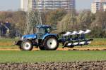 New Holland Schlepper beim Pflügen gesehen in Amsterdam am Flughafen an der Polderbahn 1.11.2014