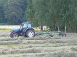 New Holland TM 115 mit Schwader bei der Heuernte in der Gemarkung von 36100 Petersberg-Marbach